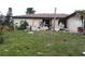 Exterior view of the house with debris scattered around the yard and damaged windows at 1627 Baywinds Ln, Sarasota, FL 34231