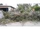 Exterior view of the house with debris scattered around the yard and damaged trees at 1627 Baywinds Ln, Sarasota, FL 34231