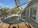 Damaged pool enclosure with view of tropical landscaping and bright blue sky at 1627 Baywinds Ln, Sarasota, FL 34231