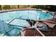 View of a pool with debris floating on the surface and scattered around the pool deck at 1627 Baywinds Ln, Sarasota, FL 34231