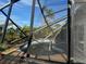 Damaged pool enclosure with view of tropical landscaping and bright blue sky at 1627 Baywinds Ln, Sarasota, FL 34231