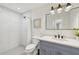 Bathroom with a blue vanity, black hardware, framed mirror, and tiled walk-in shower at 2202 Waldemere St, Sarasota, FL 34239