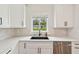 Close-up of the updated kitchen with white cabinets and stainless steel dishwasher and sink at 2202 Waldemere St, Sarasota, FL 34239