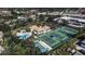 Aerial view showcasing the community pool, tennis courts, and clubhouse amenities nestled among trees and lush landscaping at 27 Inlets Blvd # 27, Nokomis, FL 34275