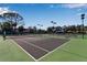 A well-maintained tennis court with a classic green surface, set against a backdrop of trees and a clear blue sky at 27 Inlets Blvd # 27, Nokomis, FL 34275