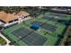 Aerial view of tennis courts with green surface and netting, surrounded by buildings at 27 Inlets Blvd # 27, Nokomis, FL 34275