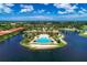 Aerial view of community clubhouse and pool on a beautiful day, located on a peninsula surrounded by a lake at 272 Maraviya Blvd, Nokomis, FL 34275