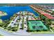 Aerial view of a waterfront community with a clubhouse, pool, and tennis courts, surrounded by lush landscaping at 272 Maraviya Blvd, Nokomis, FL 34275