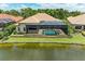 Back of house showcasing an enclosed pool with mature landscaping, viewed from the pond at 272 Maraviya Blvd, Nokomis, FL 34275