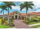 A luxurious home exterior with tropical landscaping, a paver driveway, and three car garage at 272 Maraviya Blvd, Nokomis, FL 34275