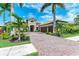 Picture-perfect exterior view of home with lush landscaping, a red tile roof and a paver driveway at 272 Maraviya Blvd, Nokomis, FL 34275