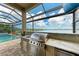 Outdoor kitchen featuring a stainless steel gas grill, marble countertops, and pool view at 272 Maraviya Blvd, Nokomis, FL 34275