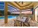 Outdoor kitchen and dining space overlooking the pool and serene lake at sunset at 272 Maraviya Blvd, Nokomis, FL 34275