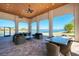 A covered patio offers lake views with outdoor furniture for relaxing or dining with ceiling fans at 272 Maraviya Blvd, Nokomis, FL 34275