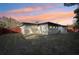 Backyard of the home at sunset that features a red wooden fence and patio with lounge chairs at 2746 Tangelo Dr, Sarasota, FL 34239