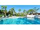 Large community pool surrounded by lush greenery, palm trees, and lounge chairs on a sunny day at 3500 El Conquistador Pkwy # 336, Bradenton, FL 34210