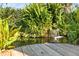 Peaceful backyard pond with small waterfall, lush plants, and wooden walkway at 3951 Palau Dr, Sarasota, FL 34241