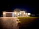 Well-lit modern home exterior at night showcasing the garage, front door and landscaping at 4396 Everglades Ter, North Port, FL 34286