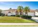 Inviting single-story home featuring a red tile roof, palm trees, and lush green lawn at 5080 Kilty E Ct, Bradenton, FL 34203