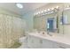 Bright bathroom with a long white vanity, large mirror, and a shower/tub combo with a patterned curtain at 5513 83Rd E Ter, Sarasota, FL 34243