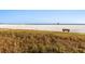 Scenic view of the beach featuring lifeguard stands and a bench amid golden, grassy dunes at 5618 Monte Rosso Rd, Sarasota, FL 34243