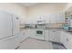 Bright kitchen featuring white cabinets, white appliances and light tile flooring, offering ample counter space at 5618 Monte Rosso Rd, Sarasota, FL 34243