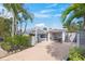 Charming home exterior with a brick driveway, a pergola-covered patio, and a carport framed by lush, tropical landscaping at 615 Avenida Del Norte, Sarasota, FL 34242