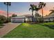 Exterior shot of home with well-manicured lawn, lush landscaping, and brick paved driveway at dusk at 6626 The Masters Ave, Lakewood Ranch, FL 34202