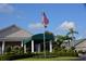 Exterior of clubhouse with manicured landscaping, palm trees, and American flag waving at 6713 Stone River Rd # 206, Bradenton, FL 34203