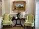 A waiting area that features two green patterned chairs, a dark wood table, and a nature painting at 6713 Stone River Rd # 206, Bradenton, FL 34203