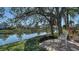 Relaxing backyard featuring a brick patio, comfortable bench, and scenic lake view at 7303 Westminster Ct, University Park, FL 34201