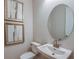 A serene powder room features an oval mirror, decorative art, and a pedestal sink at 8516 Golden Dawn Ct, Sarasota, FL 34241