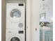 A modern laundry room with a stacked washer and dryer, adjacent to the dining area and a glimpse of the living room at 9200 Midnight Pass Rd # 20, Sarasota, FL 34242