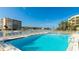 Community pool surrounded by lounge chairs overlooking the intercoastal and clear blue skies at 9200 Midnight Pass Rd # 20, Sarasota, FL 34242