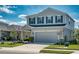 Two-story home showcasing its neat front lawn, driveway, and light gray exterior against a bright blue sky at 10811 High Noon Trl, Parrish, FL 34219