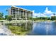 Beautiful exterior of condo building with serene pond view and lush tropical landscaping at 1105 Gulf Of Mexico Dr # 603, Longboat Key, FL 34228