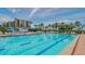 Large swimming pool with lounge chairs and blue umbrellas, close to condo building at 1105 Gulf Of Mexico Dr # 603, Longboat Key, FL 34228