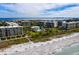 Aerial view of condo community with a pool, manicured grounds and white sand beach nearby at 1145 Gulf Of Mexico Dr # 305, Longboat Key, FL 34228