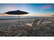 Beach sunset with chairs and umbrella overlooking ocean, perfect spot for relaxation at 1145 Gulf Of Mexico Dr # 305, Longboat Key, FL 34228