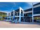 Stylish beachfront building featuring modern architecture, private balconies, and a lounge area with plenty of seating under blue umbrellas at 1145 Gulf Of Mexico Dr # 305, Longboat Key, FL 34228