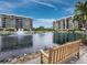 Exterior view of two buildings overlooking a lake with water fountains and a wooden bench at 1145 Gulf Of Mexico Dr # 305, Longboat Key, FL 34228