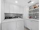 Well-lit laundry room with modern appliances, white cabinetry, and decorative tile backsplash at 1145 Gulf Of Mexico Dr # 305, Longboat Key, FL 34228