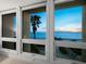 Large windows frame a picturesque ocean view with palm trees from the condo at 1145 Gulf Of Mexico Dr # 305, Longboat Key, FL 34228