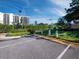 Condo parking area with electric vehicle charging station, landscaping, and building in background at 1145 Gulf Of Mexico Dr # 305, Longboat Key, FL 34228