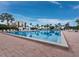 Wide view of a large pool with lounge chairs and palm trees against a bright blue sky at 1145 Gulf Of Mexico Dr # 305, Longboat Key, FL 34228