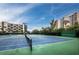 Two tennis courts with green and blue surfaces, palm trees and condo buildings in the background at 1145 Gulf Of Mexico Dr # 305, Longboat Key, FL 34228