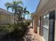 A side view of a home with tropical palm trees and brick sidewalk at 11629 Garessio Ln, Sarasota, FL 34238