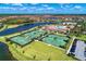 Aerial view showcases tennis courts and a clubhouse by the lake, providing many community amenities at 12510 Ghiberti Cir # 102, Venice, FL 34293