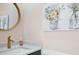 Stylish half bathroom features a gold faucet, speckled countertop, gold circular mirror and pretty flower artwork at 1555 Napoli W Dr, Sarasota, FL 34232