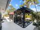 Beautiful courtyard with a black pergola, fountain, pavers, and a variety of potted plants in a tranquil outdoor setting at 1627 Bayshore Dr, Englewood, FL 34223